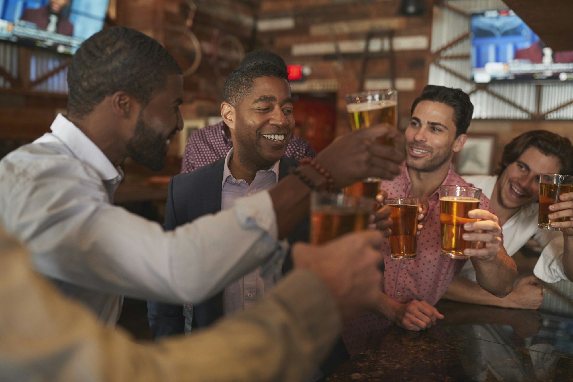 Group Of Male Friends On Night Out For Bachelor Party In Bar Making Toast Together